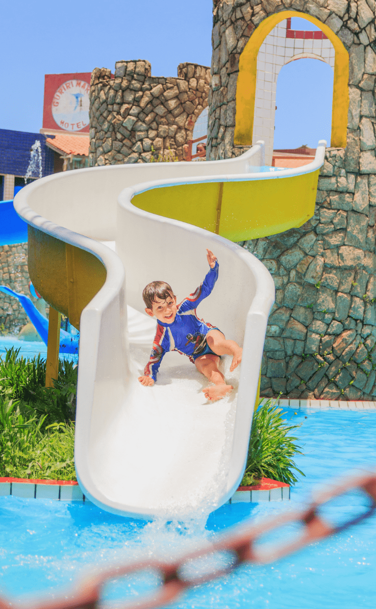 Um criança super feliz escorregando em um toboágua infantil do playground aquático